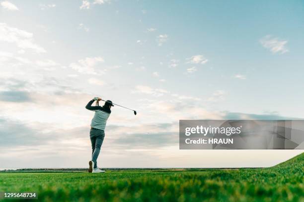 club de golfista masculino en el campo durante la puesta del sol - columpiarse fotografías e imágenes de stock