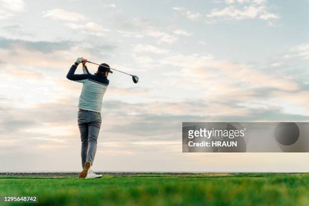 sportler abschlagen auf kurs bei sonnenuntergang - golfschwung stock-fotos und bilder