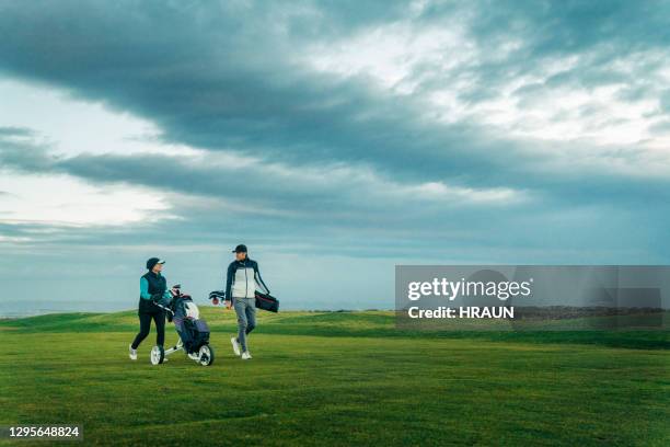 male and female golfers walking with bags - male golfer stock pictures, royalty-free photos & images