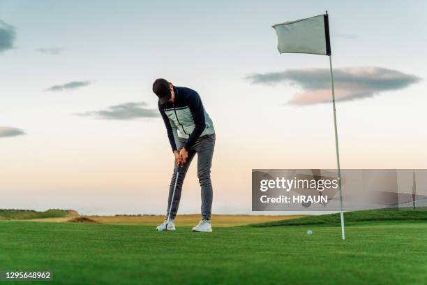 sportsman die een schot op golf neemt die gras zetten - golfvlag stockfoto's en -beelden