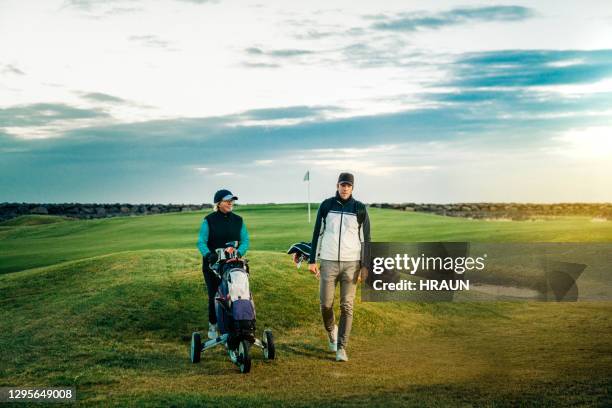 female and male golfers walking with bags - golf player stock pictures, royalty-free photos & images