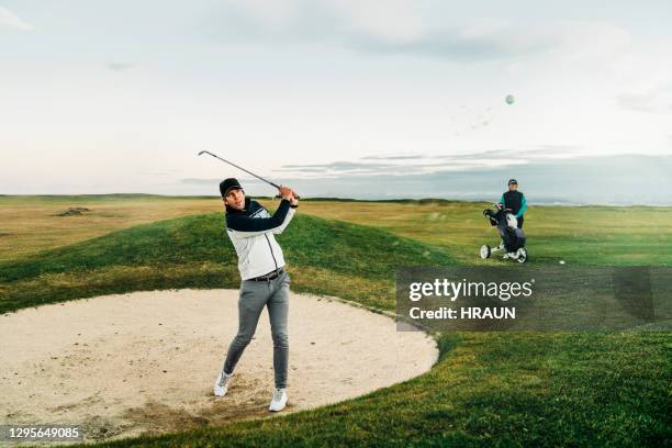 male golfer hitting ball from sand trap at sunset - sand trap stock pictures, royalty-free photos & images