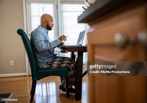 man on video conference while wearing pajama pants - pajamas fotografías e imágenes de stock