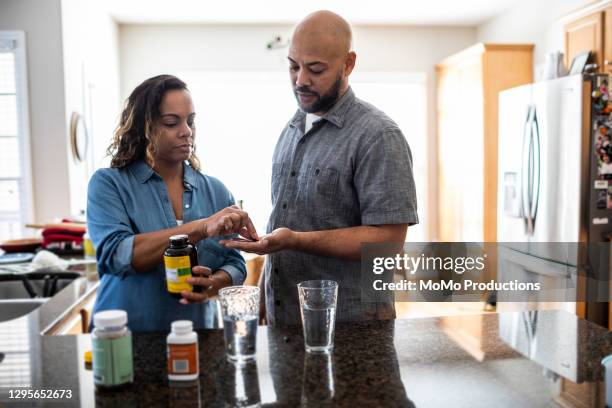 husband and wife taking vitamins at home - woman look straight black shirt stock pictures, royalty-free photos & images