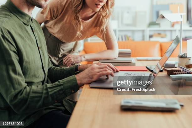 anonymous businessman in a green shirt working on his laptop computer while getting help from his coworker - a close up - green shirt stock pictures, royalty-free photos & images