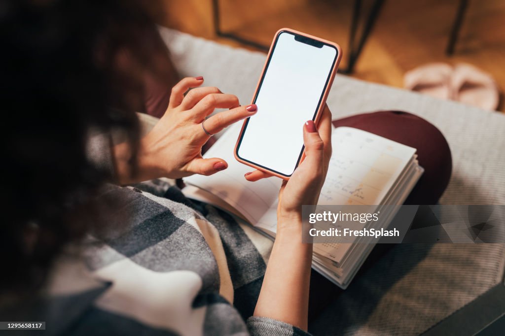 Anonieme vrouw die haar Mobiele Telefoon thuis gebruikt (Leeg Scherm, Ruimte van het Exemplaar)