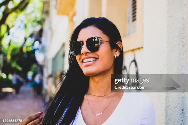 una joven con aparatos ortopédicos y gafas oscuras, en la ciudad de porto alegre - braces fotografías e imágenes de stock