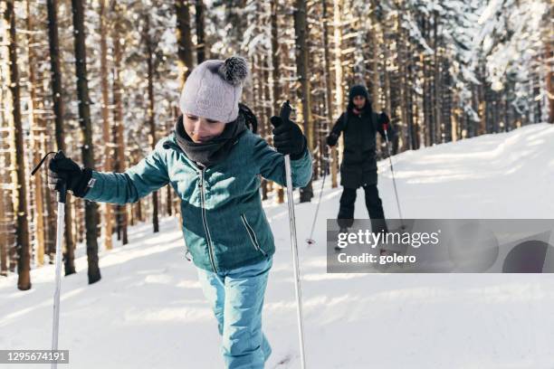 小女孩在滑雪與家人在陽光明媚的雪福雷斯特 - 越野滑雪 個照片及圖片檔