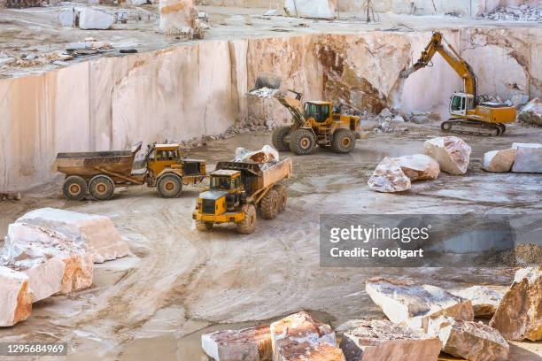 construction vehicles working in marble quarry with oversized marble blocks - mining natural resources stock pictures, royalty-free photos & images