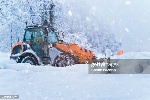 front loader removes tons of snow from a country road in heavy snowfall - snow removal stock pictures, royalty-free photos & images