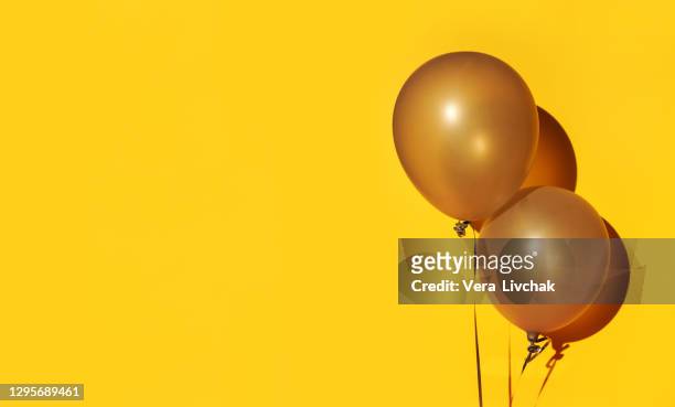festive minimalistic decorative balloons on yellow background with copy space - anniversary celebration stock-fotos und bilder
