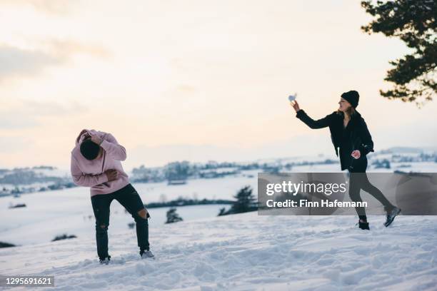 snowball fight in winter landscape young couple having fun - ducking stock pictures, royalty-free photos & images