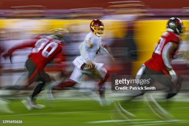 Quarterback Taylor Heinicke of the Washington Football Team scrambles past outside linebacker Jason Pierre-Paul of the Tampa Bay Buccaneers during...