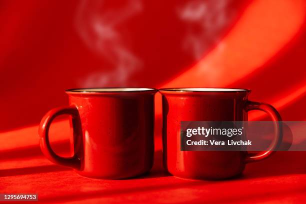 red cups of coffee or tea on black background - red mug stock pictures, royalty-free photos & images