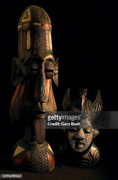 two african ceremonial masks in black limbo with warm lighting - tribal art stock pictures, royalty-free photos & images