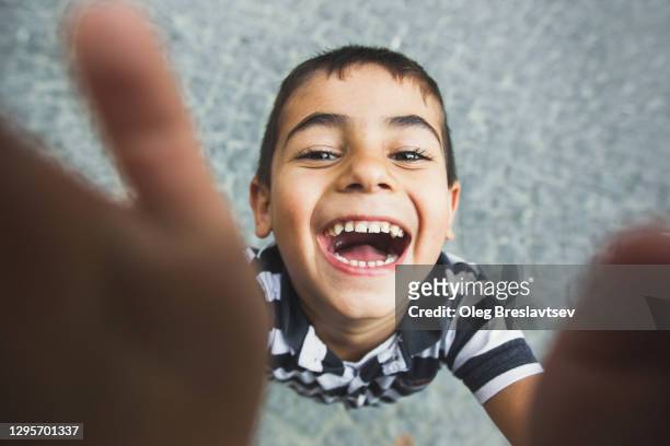 close-up funny portrait of turkish toddler boy touching camera lens with finger and taking selfie - ethnies du moyen orient photos et images de collection