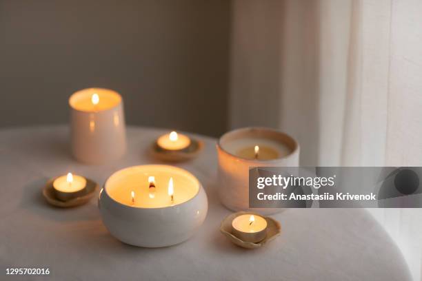 scented candles in ceramic bowls on linen tablecloth at home. - dark room foto e immagini stock