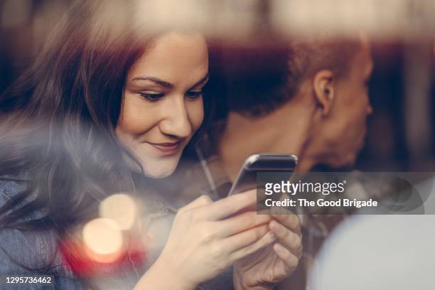 woman looking at smart phone in bar - mid adult men stock pictures, royalty-free photos & images
