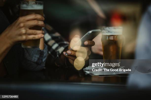 cropped image of friends looking at smart phone in bar - smart devices imagens e fotografias de stock