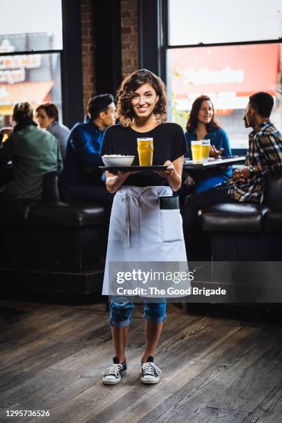 portrait of waitress carrying food and drink on serving tray in bar - man tray food holding stock pictures, royalty-free photos & images