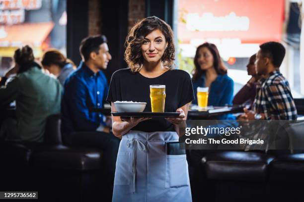 portrait of smiling waitress carrying food and drink on serving tray in bar - waiter stockfoto's en -beelden