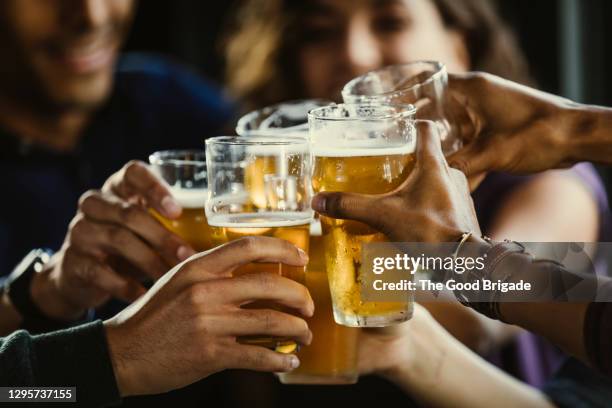 group of friends toasting beer glasses at table in bar - friends in restaurant bar stockfoto's en -beelden