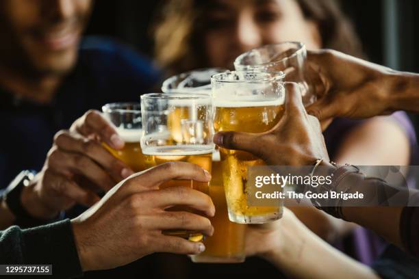 group of friends toasting beer glasses at table in bar - beer alcohol stock pictures, royalty-free photos & images