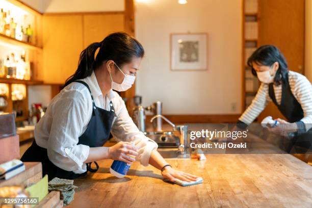 two women wearing a mask, carefully wipe a counter  and enthusiastically disinfect in preparation for opening - disinfection services stock pictures, royalty-free photos & images