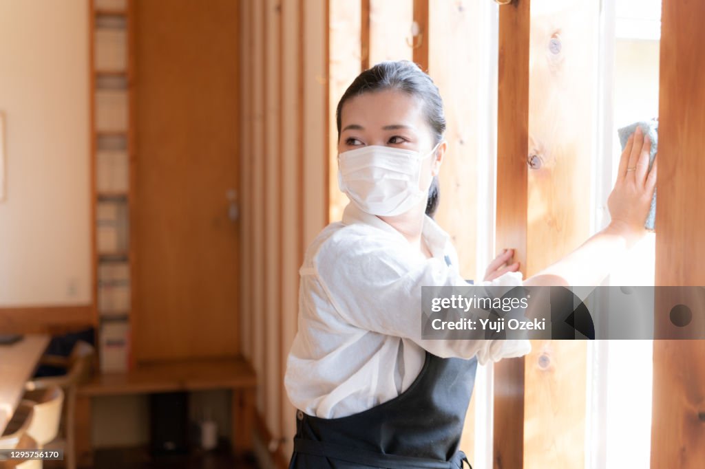 Asian Young adult woman wearing a mask, Carefully wipe and enthusiastically disinfect in preparation for opening