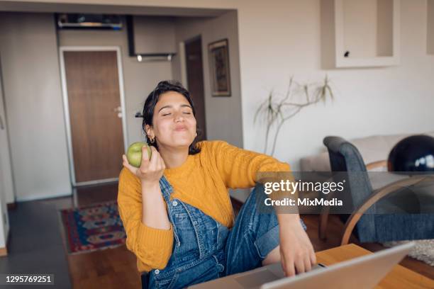 junge studenterfrischend mit einem apfel während des studiums online - frau apfel stock-fotos und bilder