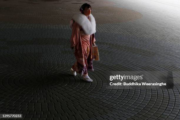 Young Japanese woman dressed in traditional kimono and wearing a face mask leaves after she attended a Coming-of- Age ceremony at Koshien national...