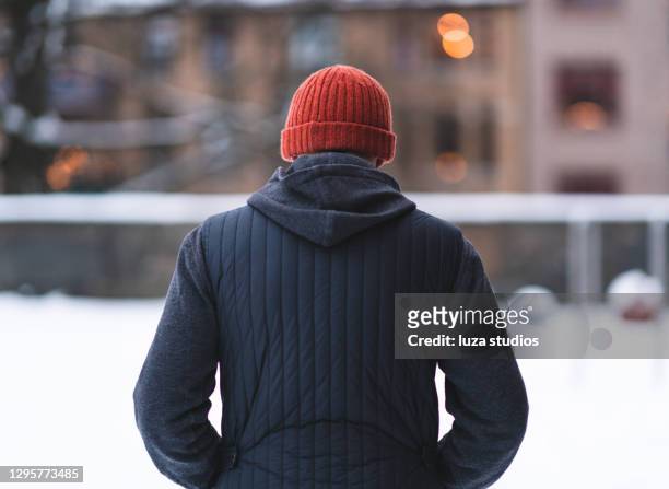 dietro un uomo camminare nella neve - cappello di lana foto e immagini stock