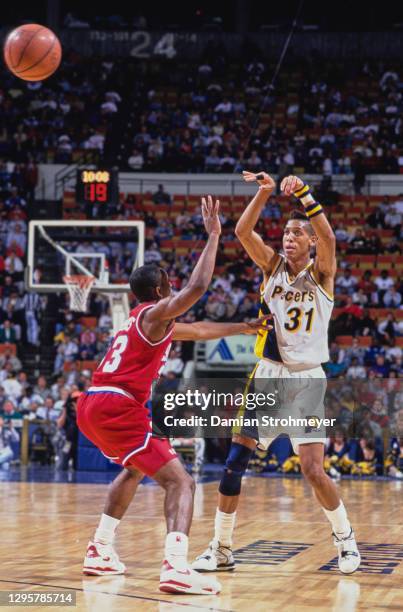 Reggie Miller, Shooting Guard for the Indiana Pacers passes the basketball over Hersey Hawkins of the Philadelphia 76ers during their NBA Central...