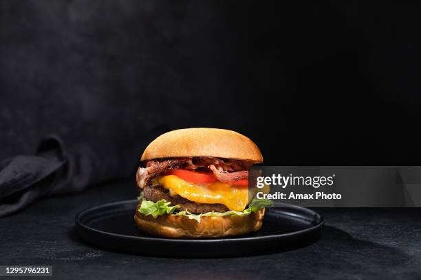 hamburguesa de queso con tocino sobre fondo negro oscuro - hamburguesa con queso y tocino fotografías e imágenes de stock