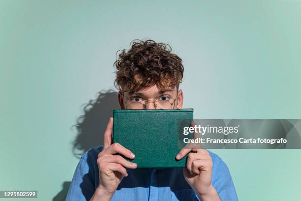 man covering face with book - rougir photos et images de collection