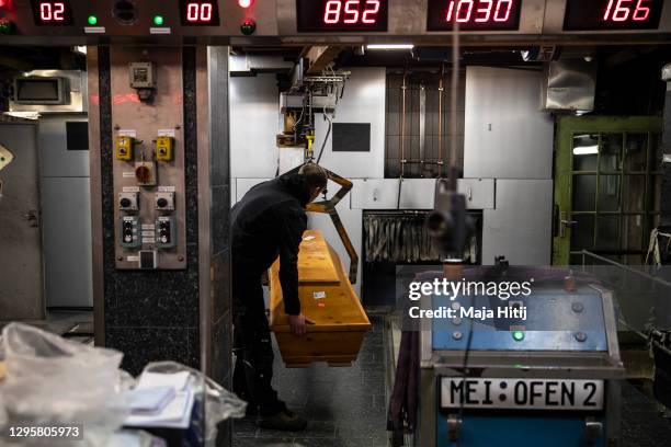 Worker moves a casket to be incinerated at a crematorium amongst coffins mainly filled with Covid-19 victims during the second wave of the...