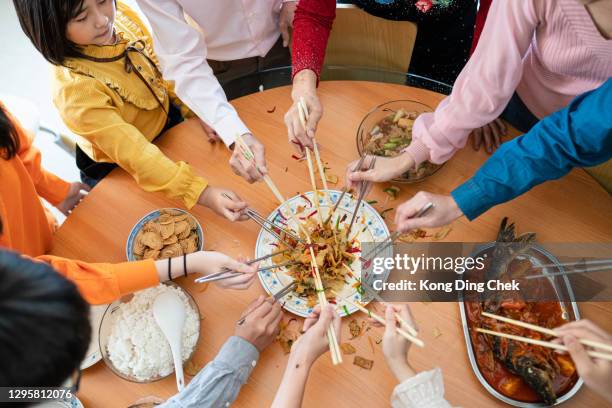 asian chinese multi generation family celebrates chinese traditional new year with a prosperity toss or “yee sang”-  lou sang - prosperity toss stock pictures, royalty-free photos & images