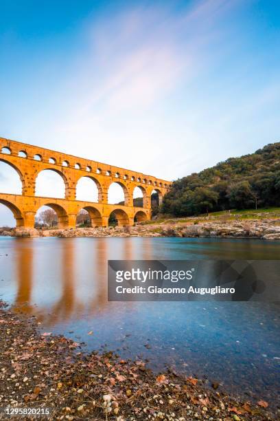 the roman aqueduct pont du gard reflected in the water, nimes, provence, france - pont du gard aqueduct stock pictures, royalty-free photos & images