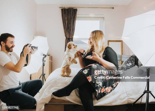 body positive social media icon and her dog perform in a small bedroom with her boyfriend as the camera operator - photoshoot bts stock pictures, royalty-free photos & images