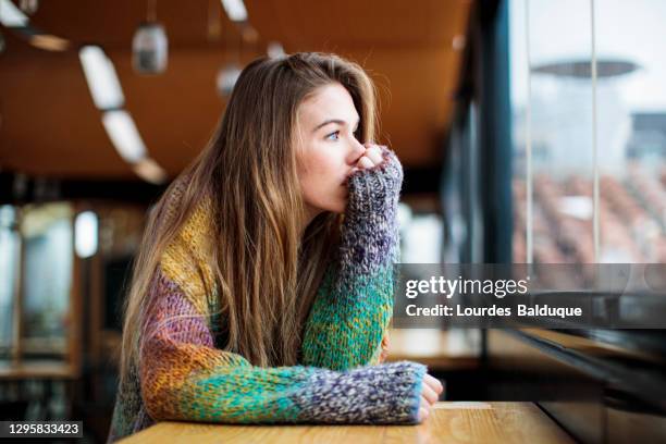 depressed girl looking out the window - depressie verdriet stockfoto's en -beelden