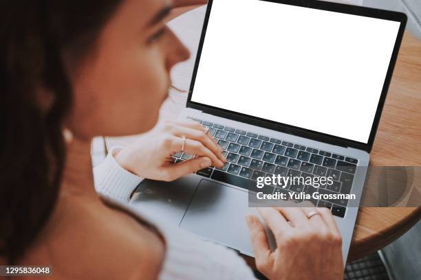 photo from behind an unrecognizable woman in profile using a laptop with a white screen. close-up - profile laptop sitting stock pictures, royalty-free photos & images