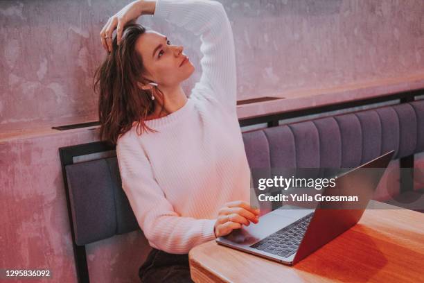 a beautiful woman in a beautiful cafe using a laptop and dreams big. - dream big stockfoto's en -beelden