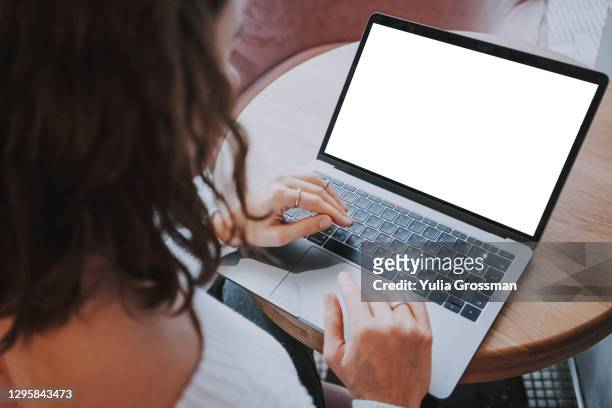 photo from behind an unrecognizable woman using a laptop with a white screen. close-up - laptop stock-fotos und bilder