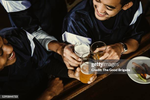 high angle view of friends toasting beer glasses at bar counter - beer bar stock-fotos und bilder