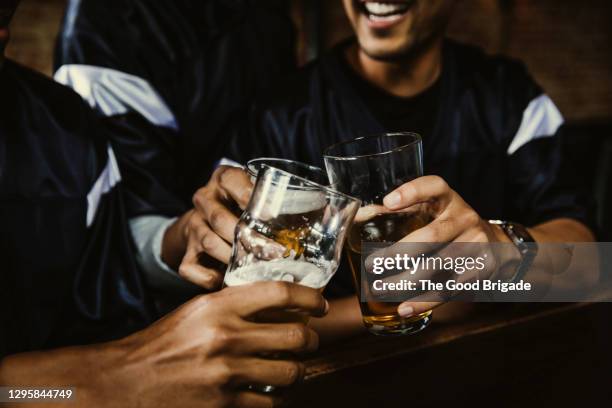 male football fans toasting beer glasses in bar - amigos bar fotografías e imágenes de stock