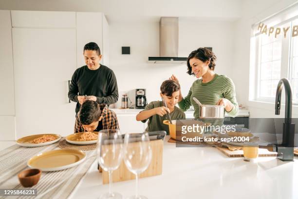 kids helping to serve the pasta.kids helping to serve the pasta. parents look happy - family wide angle stock pictures, royalty-free photos & images