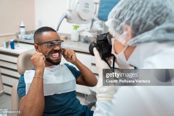 dentista fotografiando los dientes del paciente - odontología cosmética fotografías e imágenes de stock