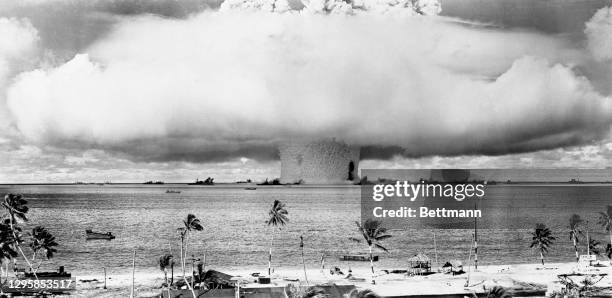 This view from the shore at Bikini shows the explosion of the atomic bomb in underwater test of July 25th, spreading over the target array of ships....