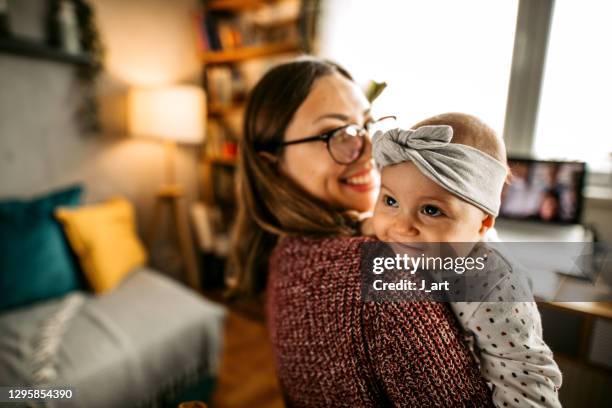 cute baby girl smiling over mothers shoulder. - au pair fotografías e imágenes de stock