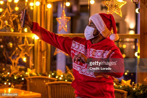 a masked mixed race man enjoying the warm cafe culture in a winter bar - hague market stock pictures, royalty-free photos & images